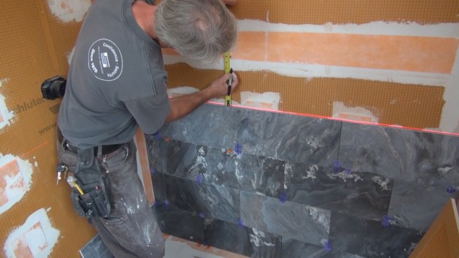 Boucher marks the shower wall for his cut. He'll install the recess box so that a full tile will fall flush with the lower edge of the box.