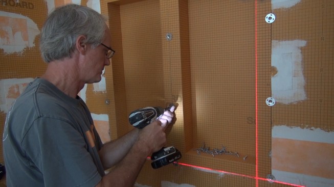Boucher screws the washers down onto the Kerdi-Board to fasten the box firmly to the framing.