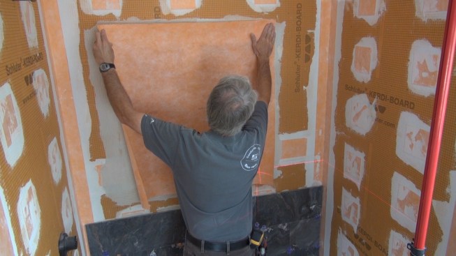 Boucher lays his pre-cut piece of Kerdi membrane over the two boxes, completely covering the mortared joints.