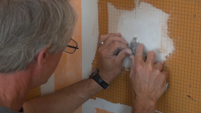 Using his knife, Boucher digs away the mortar covering the existing screw and washer that holds the Kerdi-Board to the wall stud.