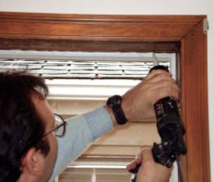 The author sets the new window against the outer stop in a bed of butyl caulk. Butyl sticks well to both aluminum and old wood, and its nonhardening formula helps it absorb seasonal movement better than other sealants.