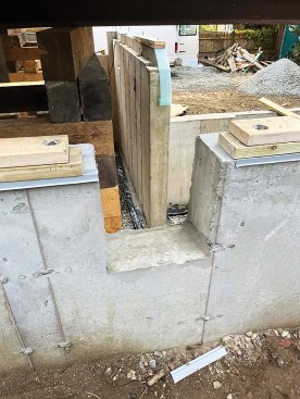 The author installed new pressure-treated sills on the concrete with a second kiln-dried layer on top of the PT plate. At the beam pockets, his crew stepped these back so they could be spliced in after the house had been set back down.