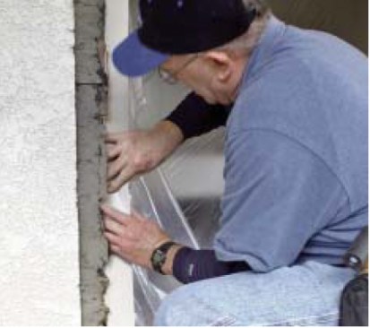 The author backs up the old building paper around the opening with vinyl coil stock, slipping it in behind the paper and underneath the stucco edge.