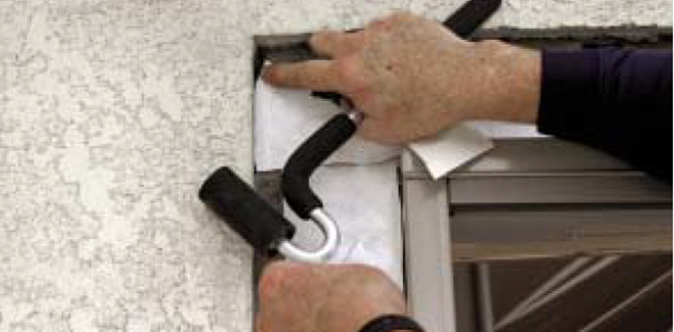At the head, he attaches a horizontal membrane to the metal head flashing, tucks it under the building paper, and laps it over the side flashings.