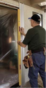 The author attaches a saw guide to the wall at a plumb layout line.