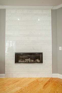 A traditional fireplace mantel was replaced with a floor-to-ceiling carrara marble surround and a gas fireplace. The installation was a learning experience for Rdone Island Kitchen and Bath when the material failed once the flames were turned on. Twice. Ultimately, the design team found a way around the problem. Listen as the firm's director of design explains. 