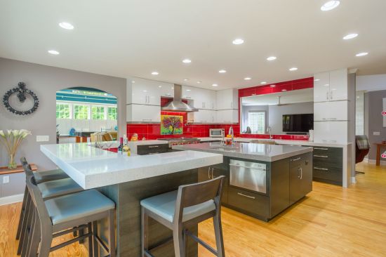 The same material can be found below the wrap-around quartz countertops; and on a custom seating bench with built-in storage. Stylish and functional, the kitchen features double the amenities, with full and mini refrigerators, standard and drawer dishwashers, dual microwaves, and two sinks, allowing for multiple activities in a kitchen that serves as a cooking, eating, and gathering space for a festive family.