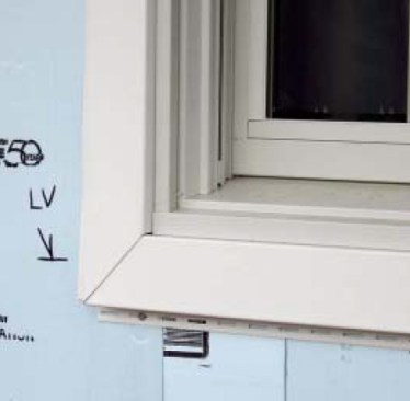 The base piece of the window surround is nailed through the foam into the window rough frame (left), and the matching top piece snaps into place over it.