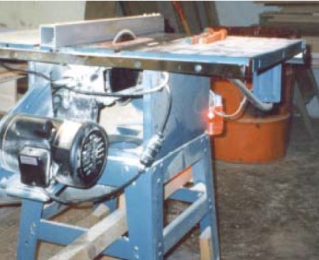 After his accident, the author equipped his table saw with a clearly visible running light; now he knows if the saw is on even when heβs wearing hearing protection. Note the absence of a blade guard between the underside of the sawβs blade and its dust-collection port.