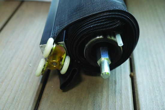 A pin at the other end of the rolled-up assembly fits into the mounting bracket, while the bottom of the screen terminates with a heavy aluminum bar with rollers mounted to the ends.