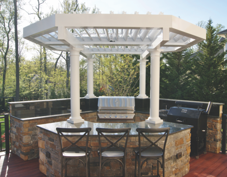 This outdoor kitchen features granite countertops and cabinets faced with stacked stone. Rain or shine, some shelter is provided by an Equinox louvered octagonal pergola, supported by custom PVC columns.