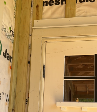 Close up of the trim and flashing details for doors at the Queen of Zero project. Note the 1x trim that extended the door jambs and two-step head flashing.