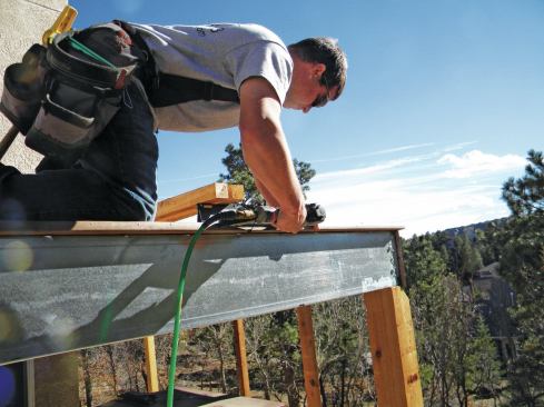 Robert Shaw of Colorado Deck and Framing installs edge trim on a deck in Colorado Springs, Colo. Eighteen-gauge stainless steel finish nails hold the trim in place until the glue dries. One nail per deck board is more than enough.