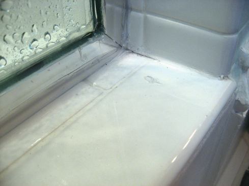 This grout crack formed within an hour of the door track being screwed to the wall.
