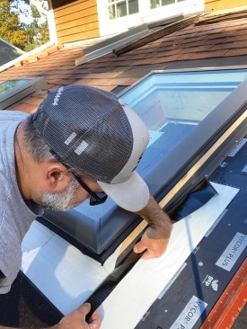 I carefully followed the layout lines that I marked on the roof-deck flashing as I installed the white flexible flashing, folding it at a 90-degree angle so that it would adhere tightly both to the side of the skylight and to the roof-deck flashing.