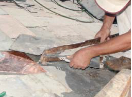 A slate cutter’s lever arm is powerful enough to readily shear through slate but allows fine control for careful cutting. Here, slate roofing contractor John Kuhn uses the tool to nibble out a half circle for a vent pipe penetration.