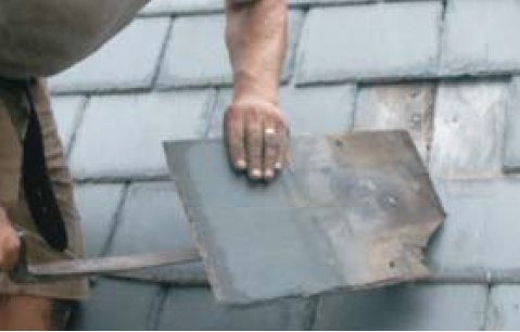 The roofer slides the tool under the slate and hooks the nails out with a combined pulling and levering action.
