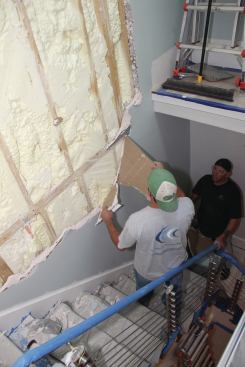 For retrofits such as the stairwell party wall shown here, crew tears off existing drywall by hand.