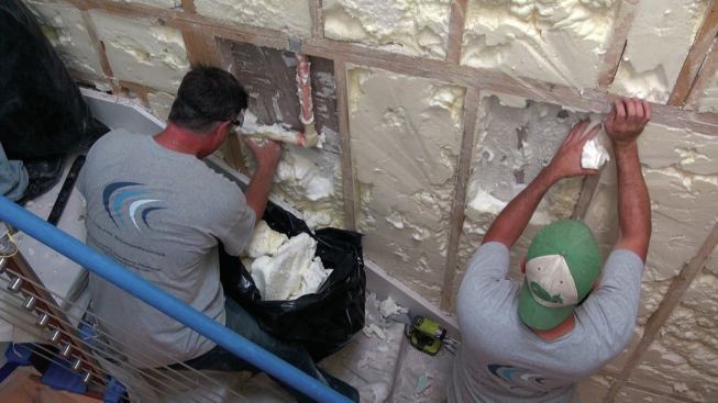 Being careful not to damage existing plumbing and wiring, the crew tears out any spray foam insulation by hand and replaces it with special acoustic rock wool fiber batts.
