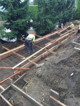 Both the inner and outer walls of the earth planter/retaining wall assembly - required to stabilize the sloped site - are supported by a steel-reinforced spread footing.