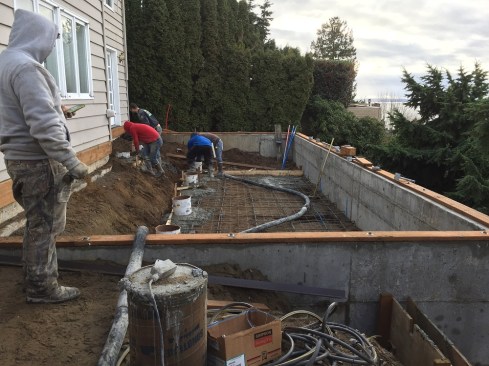 Crew members fill the piers with concrete from the pumper truck, prior to pouring the spa slab.