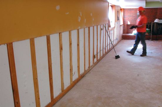 On walls built against concrete, remove drywall, but leave furring strips in place. After this photo was taken, the beadboard was also removed to aid drying.