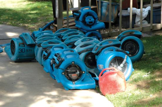 Air movers or carpet fans create a high-volume stream of air to pull moisture from the surfaces of materials into the air; a dehumidifier condenses moisture from the air into water that can be carried out of the building.