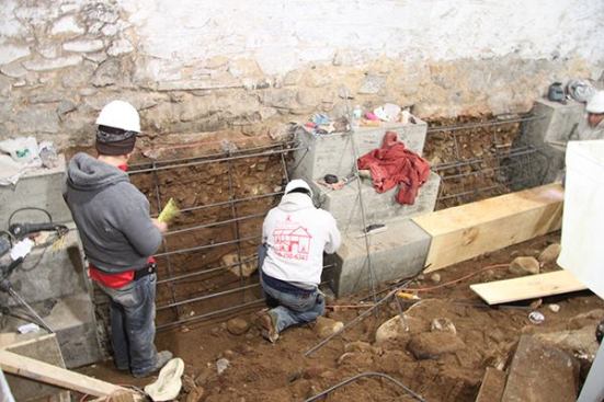 Workers place and tie rebar for buttress sections in a Brooklyn basement as part of a project to lower the basement floor. The buttress will stabilize the basement wall, which is shared with an adjacent dwelling.