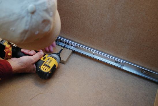 To install the drawer boxes, I first attached the slides to the cabinet side, spacing them off the bottom with a 1/2-inch-thick temporary shim. (At first I forgot the front had to be raised up an extra ¼ inch since the cabinet bottom slopes up from front to back.)