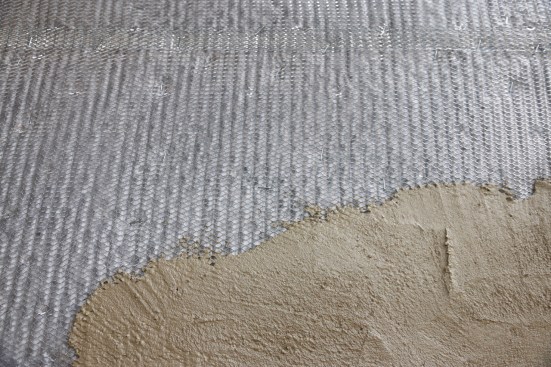 The first coat of traditional stucco is called the "scratch coat." This coat tooths into the lath and holds it onto the building. You can see here that the fabric on the Delta Dry Stucco & Stone keeps the stucco from clogging the pores of the drainage mat.