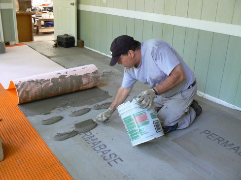 After embedding the first half of each strip of membrane in the thinset, the author rolled back the second half and repeated the process.