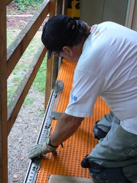 After pressing the trim into place in the mud, the author placed a concrete block at each end to hold it in place while the mud set up.