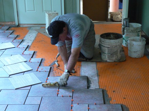 The porcelain tile used to finish the floor was applied in a pinwheel pattern, which requires two different sizes of square tiles. Usually (but not always) one tile in this pattern is twice as big as the other. In this case, the large tile was 11 3/4 inches square and the small tile was 5 3/4 inches square. With a 1/4-inch mortar joint, the size of the increments for the layout ended up an even 12 inches and 6 inches.