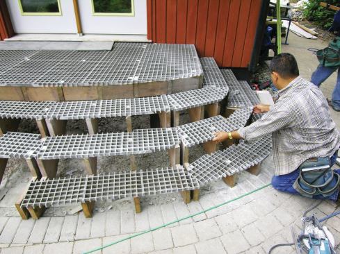 The fiberglass grating panels can be cut to fit with a circular saw. Here, the deck surface fits just beneath the door threshold, with the framing sloped slightly away from the house for drainage. 
