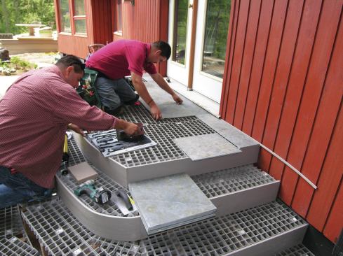 The tiles were glued to the fiberglass grating with a structural adhesive, which was applied to the back of the tile with a caulk gun and then spread with a V-notch trowel.