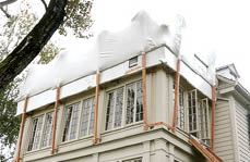 After being shrunk to its final size with high-output propane torches - a ticklish task carried out by an experienced abatement crew - the weatherproof and windproof cover remained in place for the duration of the six-week project. The debris chute visible at right was used by another contractor working in living space below.