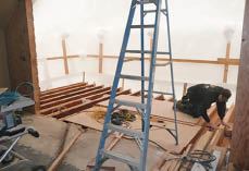 The job involved removing the existing roof, cutting down and sistering existing rafters, putting down a new roof, and then constructing a floating deck structure that was finished flush with the original bedroom floor. Much of the work was accompanied by the sound of heavy rain drumming on the plastic cover.