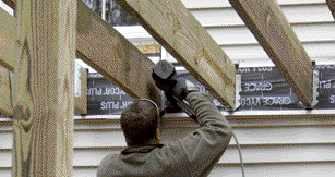 Figure 9. Resting the joists on the girder, one carpenter toenails them in place (top). A second crew member follows behind, using a metal-connector nailer to fasten the joist hangers (bottom).
