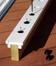 Figure 3. Lines drawn square down the side of the jig ease its alignment with the ends of the 2x4 railing. Without the lines, placing the jig to provide even spacing of the end baluster connectors would require measuring to the center of the jig's holes. To use the jig, simply place it where you want on the rail, drop in a connector, and screw.