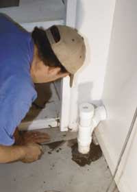 Figure 4. A second hole was hammered into the garage slab to create an additional vent sump (top). The vertical pipe was cemented in place with its open end extending just beneath the underside of the slab, minimizing the risk of blockage by an unexpectedly high water table (above). The uncemented cap on the vent line allows for later expansion, if needed.