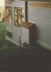 Figure 6. External vents always require a fan to provide a reliable draft. The vent pipe was secured to the fan housing with standard neoprene plumbing connectors before continuing up the wall of the house (left). The finished assembly — located on an inconspicuous outside elevation — was later boxed in for a more finished appearance (right).
