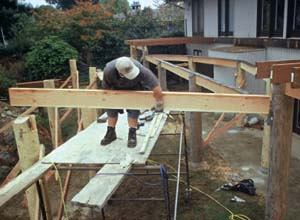 Figure 11. Before the beams are placed in their pockets, the wood is treated with a borate preservative. Note the torch-down roofing membrane applied to the beam and post tops in the background.