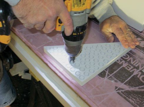 Plugs. Depending on my schedule for installing the wraps, I can plug the holes on the bench or after the wrap is installed. The PVC plugs are made from leftover scraps. I cut them with a 3/8-inch Fuller plug cutter chucked into my drill.