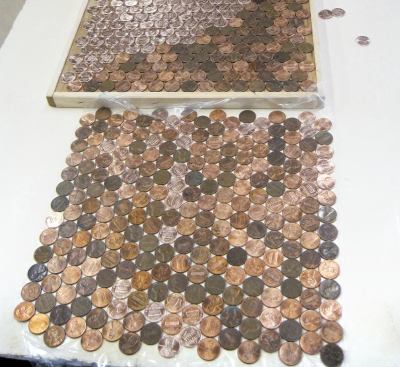 Assemble the pennies into temporary foot-square “tiles” by placing a handful of coins on a lipped plywood form and shaking it gently until they’re all lying flat and the surface is completely covered. Complete each tile by sticking a square of adhesive plastic carpet protector — a material familiar to most remodelers — to the exposed surface. Carefully turn the form over onto a stack of previously prepared tiles, separating the layers with sheets of waxed paper.
