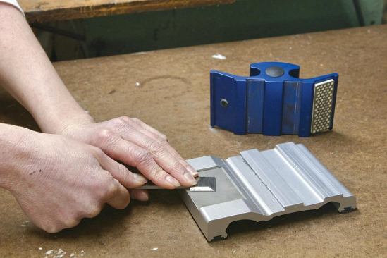 The diamond stone in the carriage hones the beveled edges of the cutting tools, and a deburring plate on the base takes the edge off the flat side.