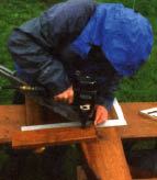 Figure 7. The author uses a framing square to be sure the seat-support 2x4s are at the correct 5-degree angle — which is a 1-in-12 pitch — as he nails them to the 4x10 posts.