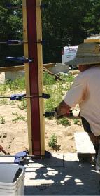 The author clamps 2x6 cladding to a column and secures it with powder-actuated pins.