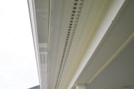 We cut saw kerfs into the edges of our soffit boards, and slip the flanges of the metal strip vents into these kerfs.