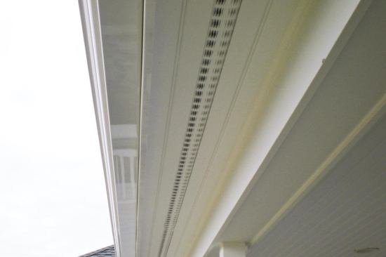 We cut saw kerfs into the edges of our soffit boards, and slip the flanges of the metal strip vents into these kerfs.
