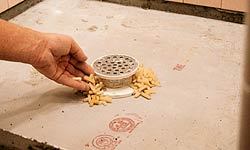To prevent mortar from plugging the drain’s weep holes, circle the drain with plastic tile spacers.